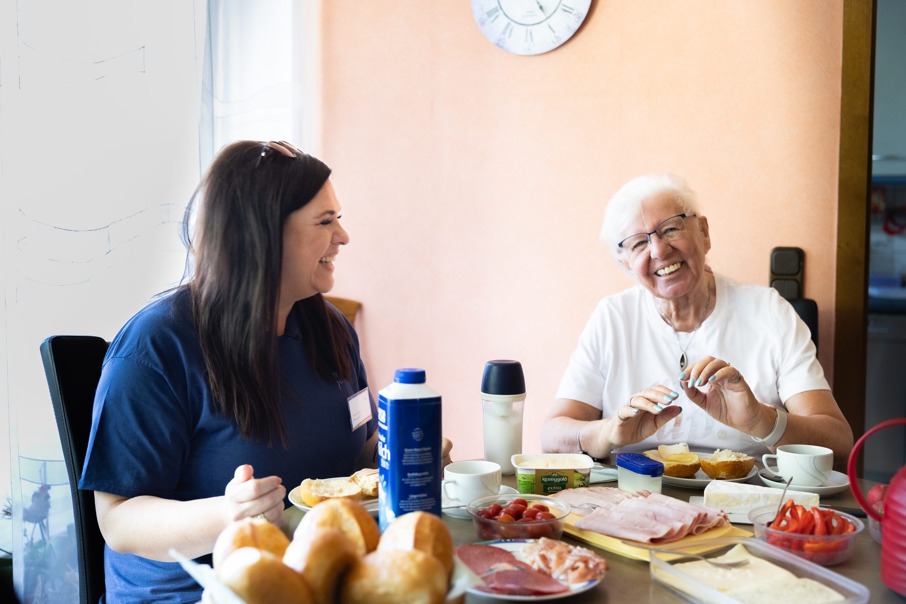 Betreuungskraft und Seniorin beim gemeinsamen Frühstück