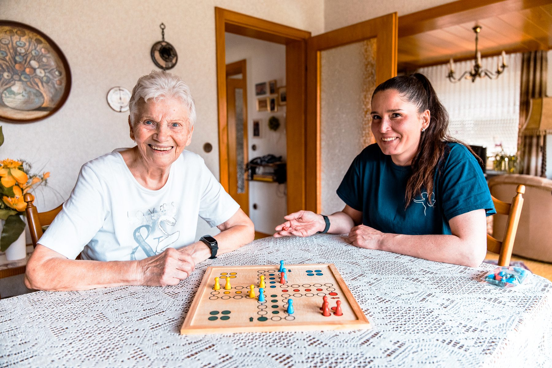 Betreuungskraft und Seniorin spielen gemeinsam am Tisch